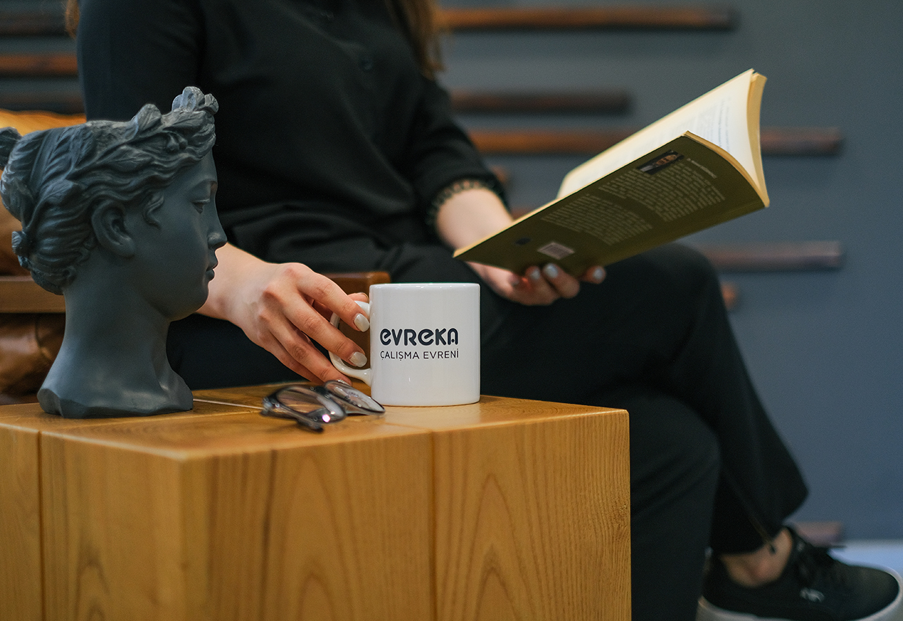 EVREKA'da markalı kupa, kitap ve sıcak ahşap detay